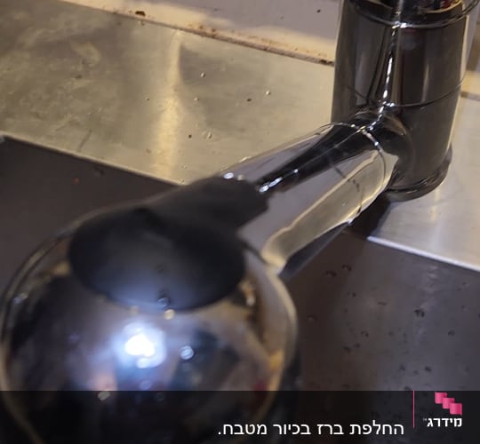 ברז מים בכיור מטבח עם זרם מים זורם
